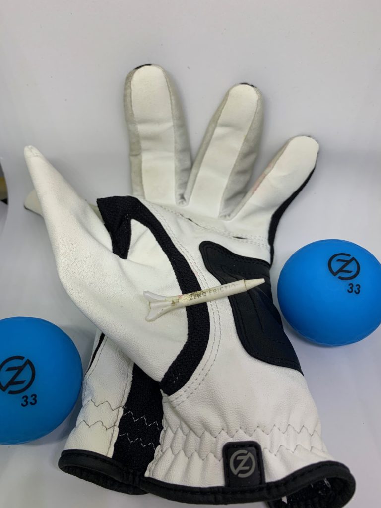 this image shows the white compression golf glove by Zero Friction and two neon blue Zero Friction balls and a single ine inch Zero Friction golf tee